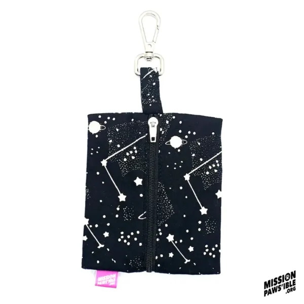 The Into The Cosmos Carry-All is a black zippered pouch adorned with white space-themed designs of constellations and planets, complete with a metal clip at the top. The Mission Paws'ible logo is situated in the bottom right corner.