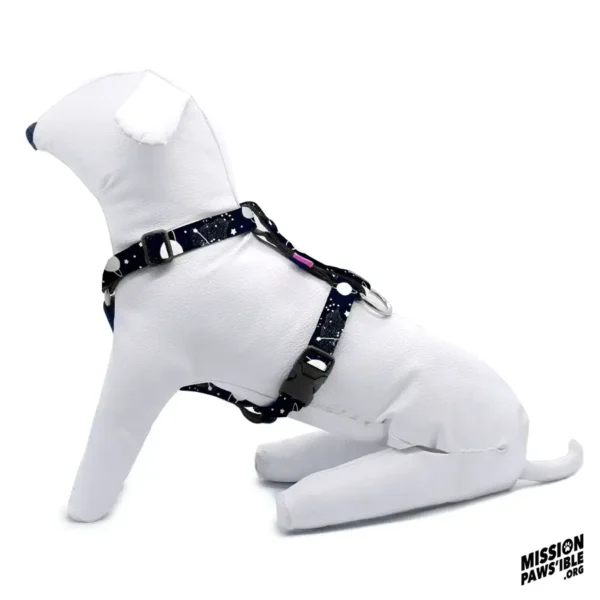 A white dog mannequin sporting the "Into The Cosmos" Adjustable Harness in a dark blue galaxy pattern, with the "Mission Paws'ible" logo in the corner.