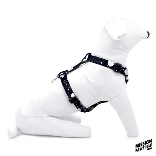 A white plush dog mannequin wearing the "Into The Cosmos Adjustable Harness," adorned with white spots, is displayed on a white background. The logo in the corner reads "Mission Pawsible.