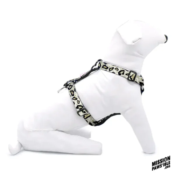 A white dog mannequin wears the Hear Me Roar Adjustable Harness in a leopard print, sitting in profile view, while the "Mission Paws’ible" logo is visible in the corner.