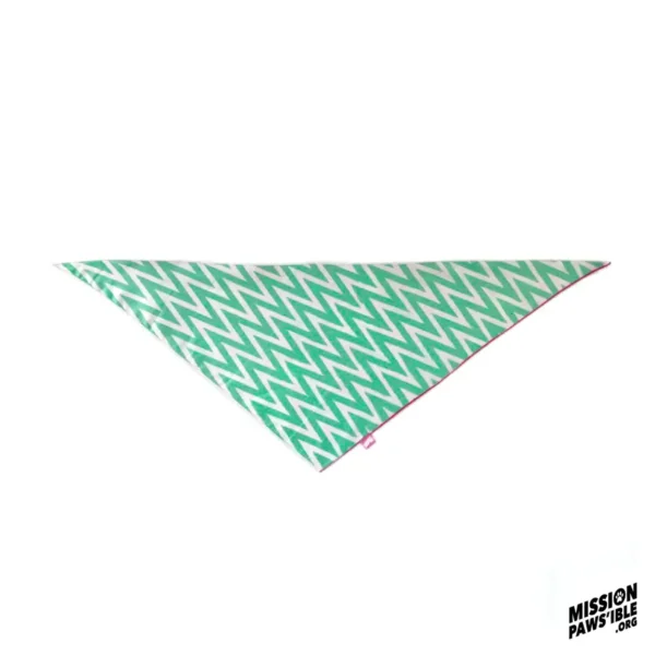 The Fruit Tingle Reversible Bandana is triangular in shape, featuring a vibrant green and white zigzag pattern with a discreet label positioned in the corner.