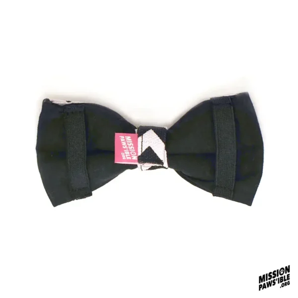 Introducing the Chevy Chase Bow Tie: a black bow tie with a pink label, showcasing a geometric design on the knot and featuring the "Mission Paws'ible" logo in the bottom right corner.