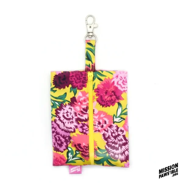 The Flower Power Yellow Carry-All is adorned with pink flowers on a yellow background and includes both a zipper and an attachment clip. The bottom corner displays the "Mission Pawsible" logo.